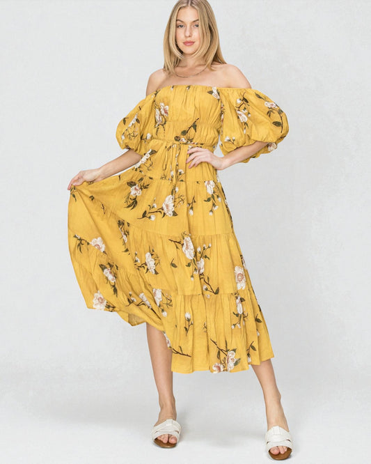 Woman wearing a yellow floral off-shoulder dress on a white background
