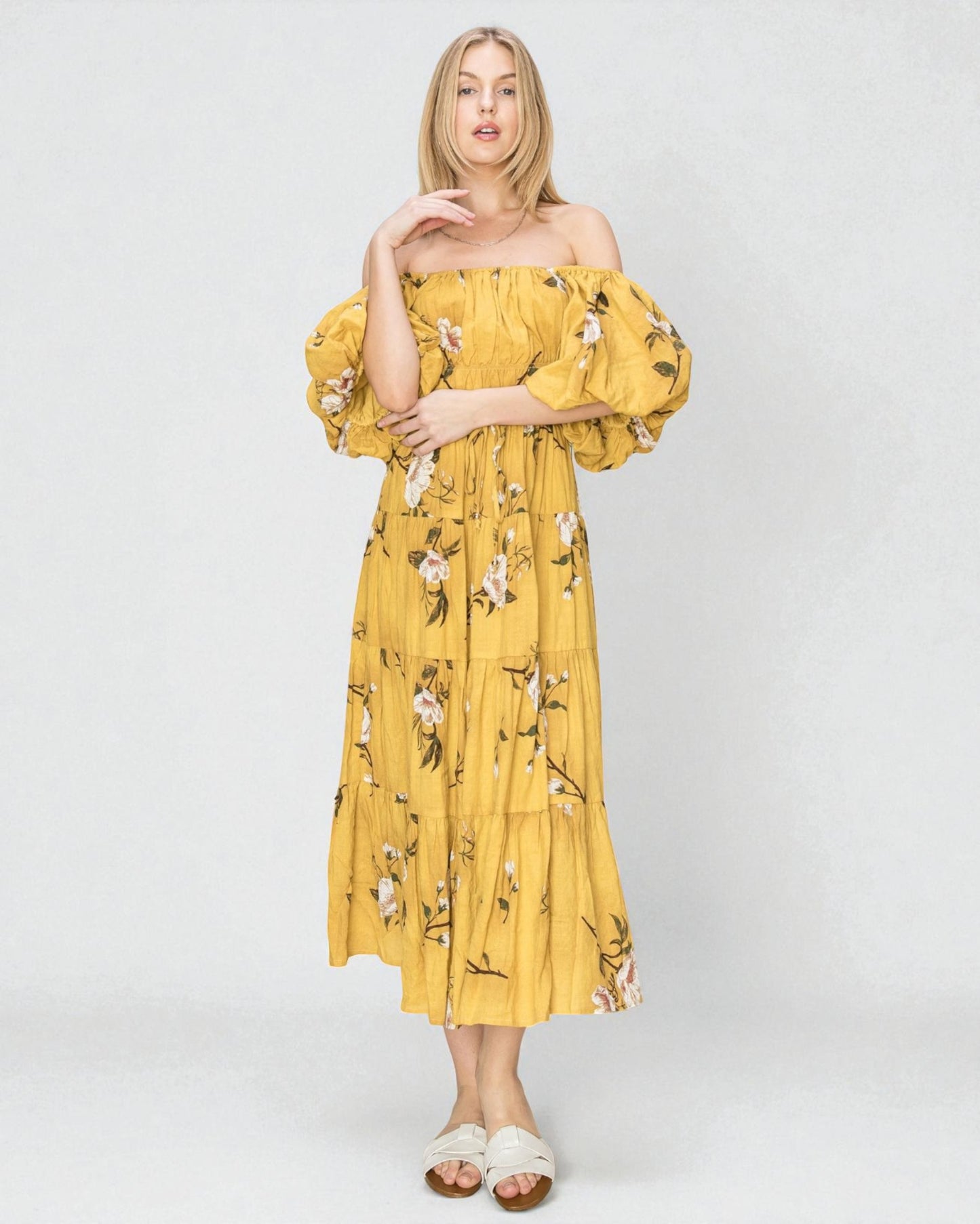 Woman wearing a yellow floral dress on a white background