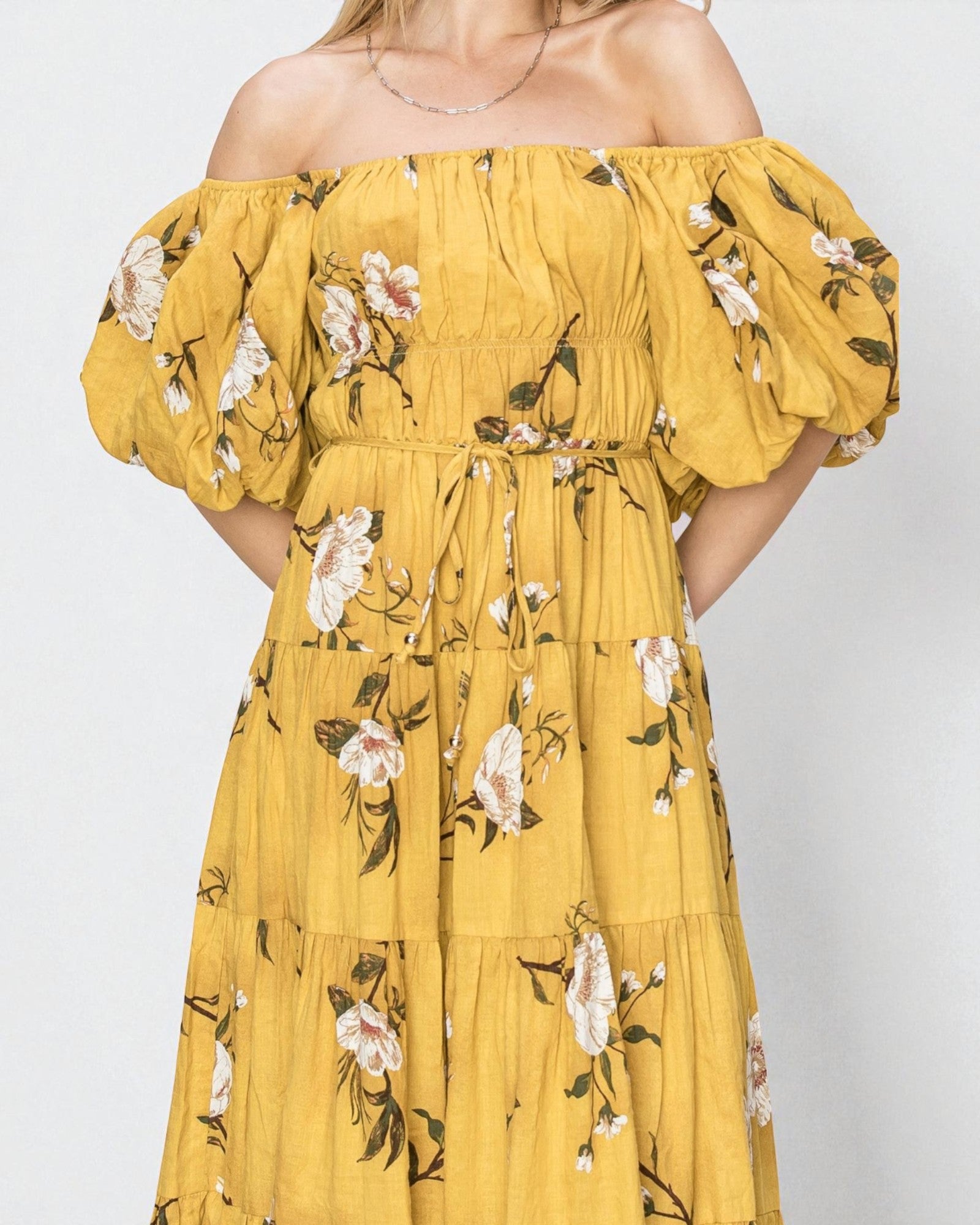 Yellow floral off-shoulder dress on a plain background
