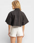Person wearing a black jacket and white shorts on a plain background