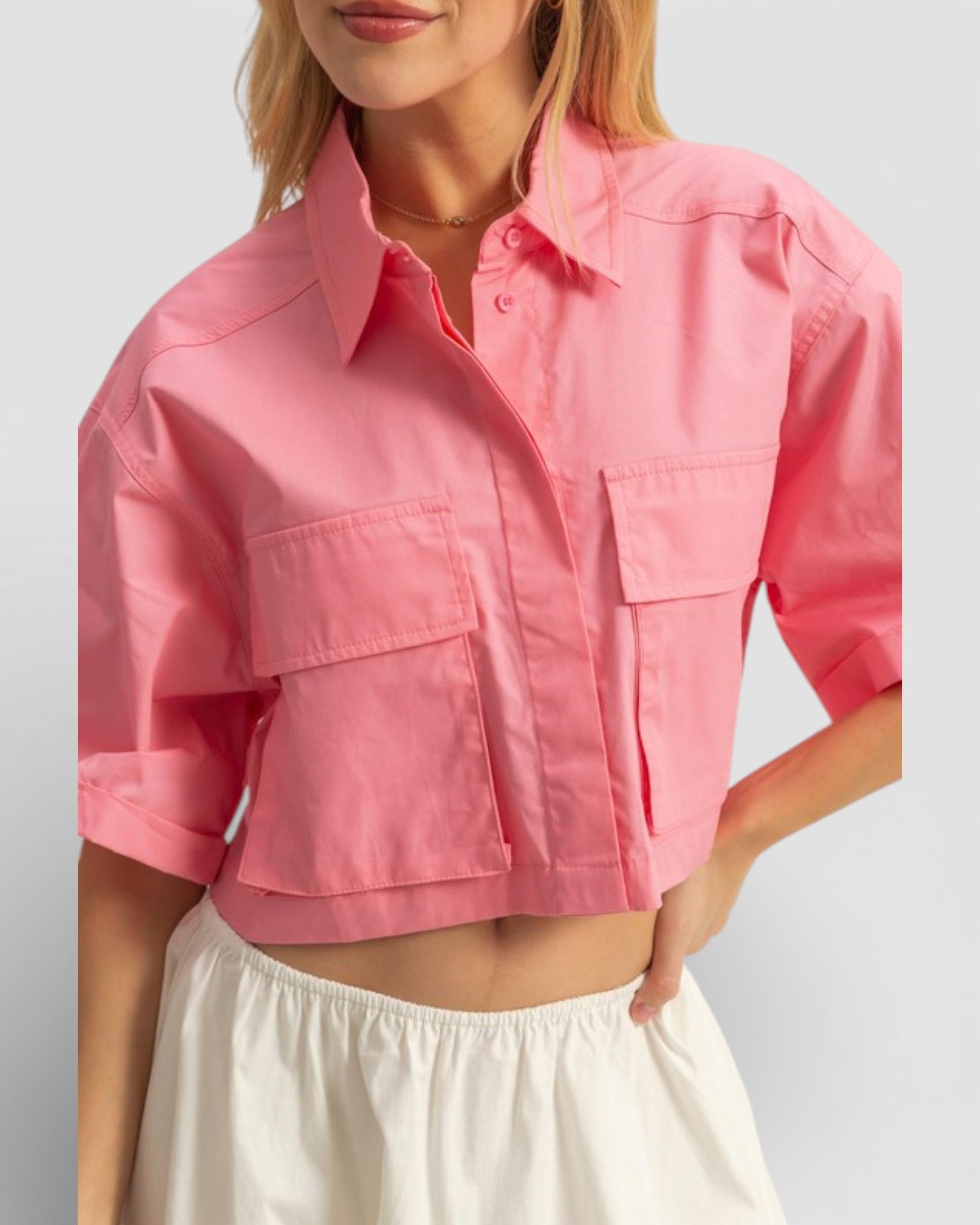 Person wearing a pink cropped shirt with a plain background