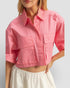 Person wearing a pink cropped shirt with a plain background