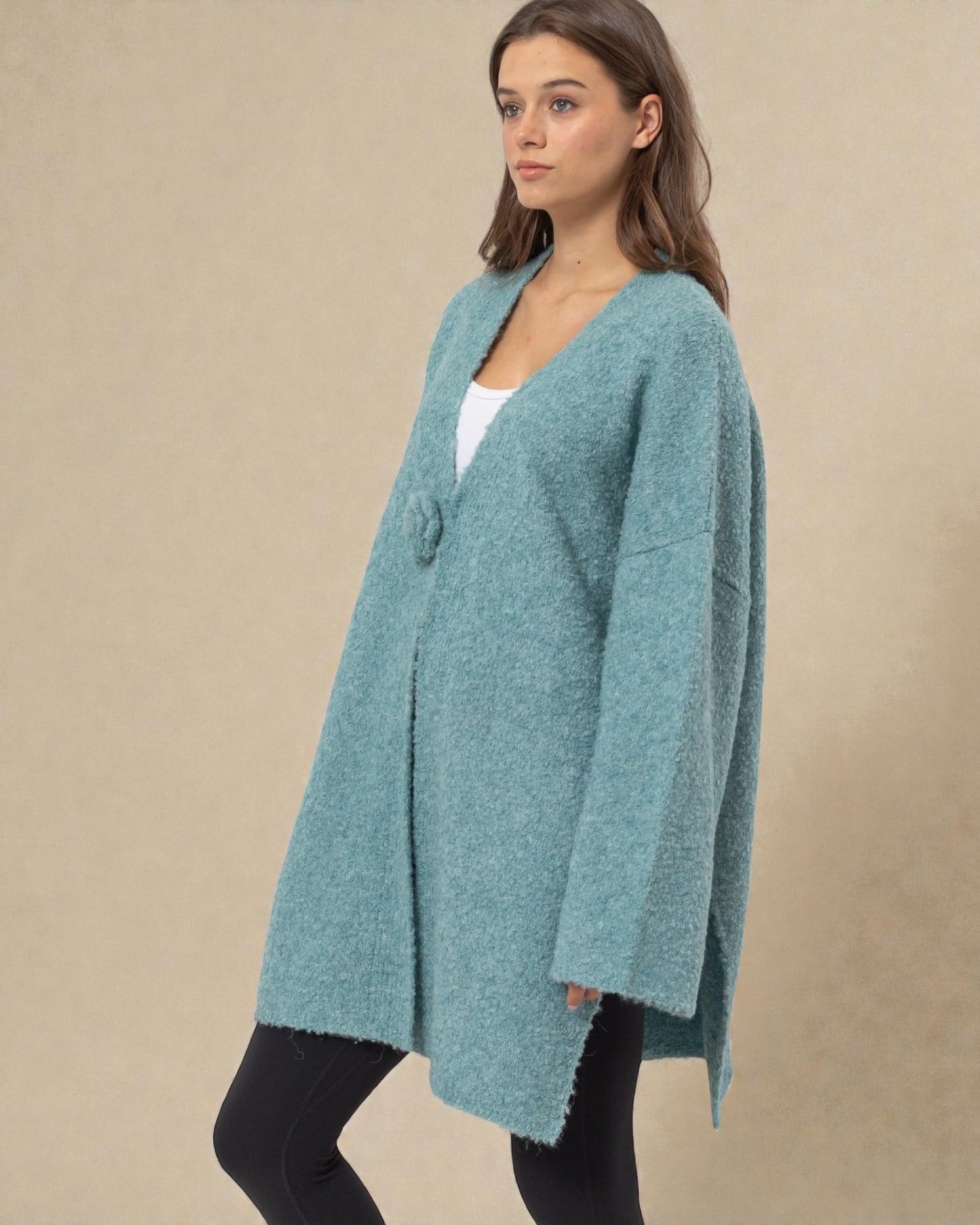 Woman wearing a teal cardigan against a beige background