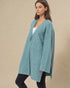 Woman wearing a teal cardigan against a beige background