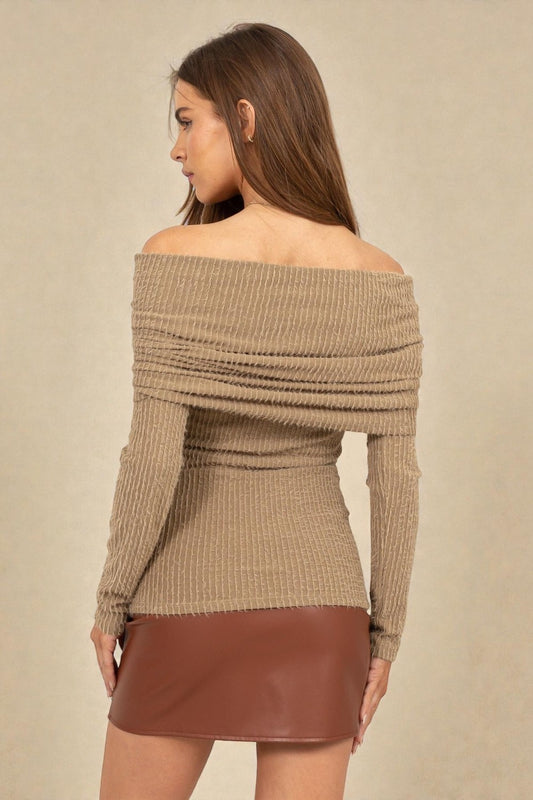 Woman wearing a beige off-shoulder sweater and brown leather skirt against a beige background