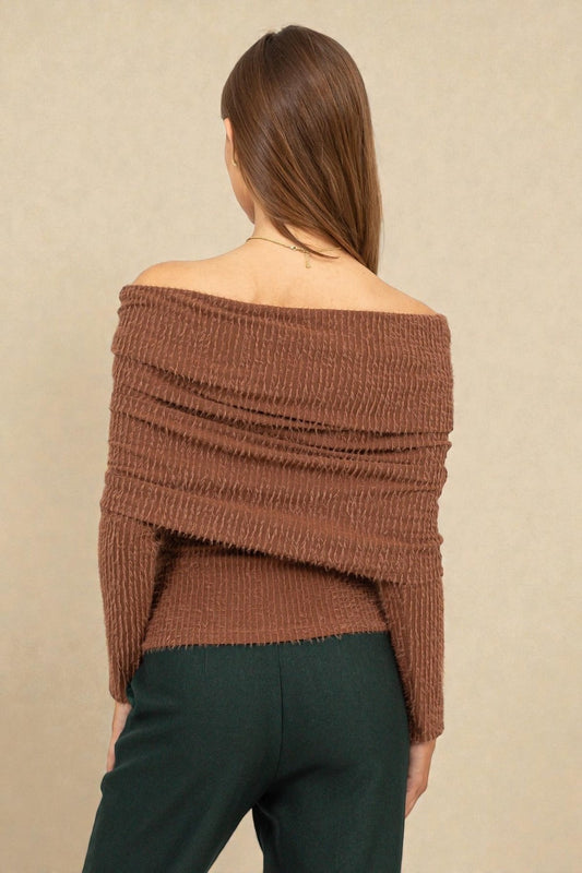 Woman wearing a brown off-shoulder sweater against a beige background