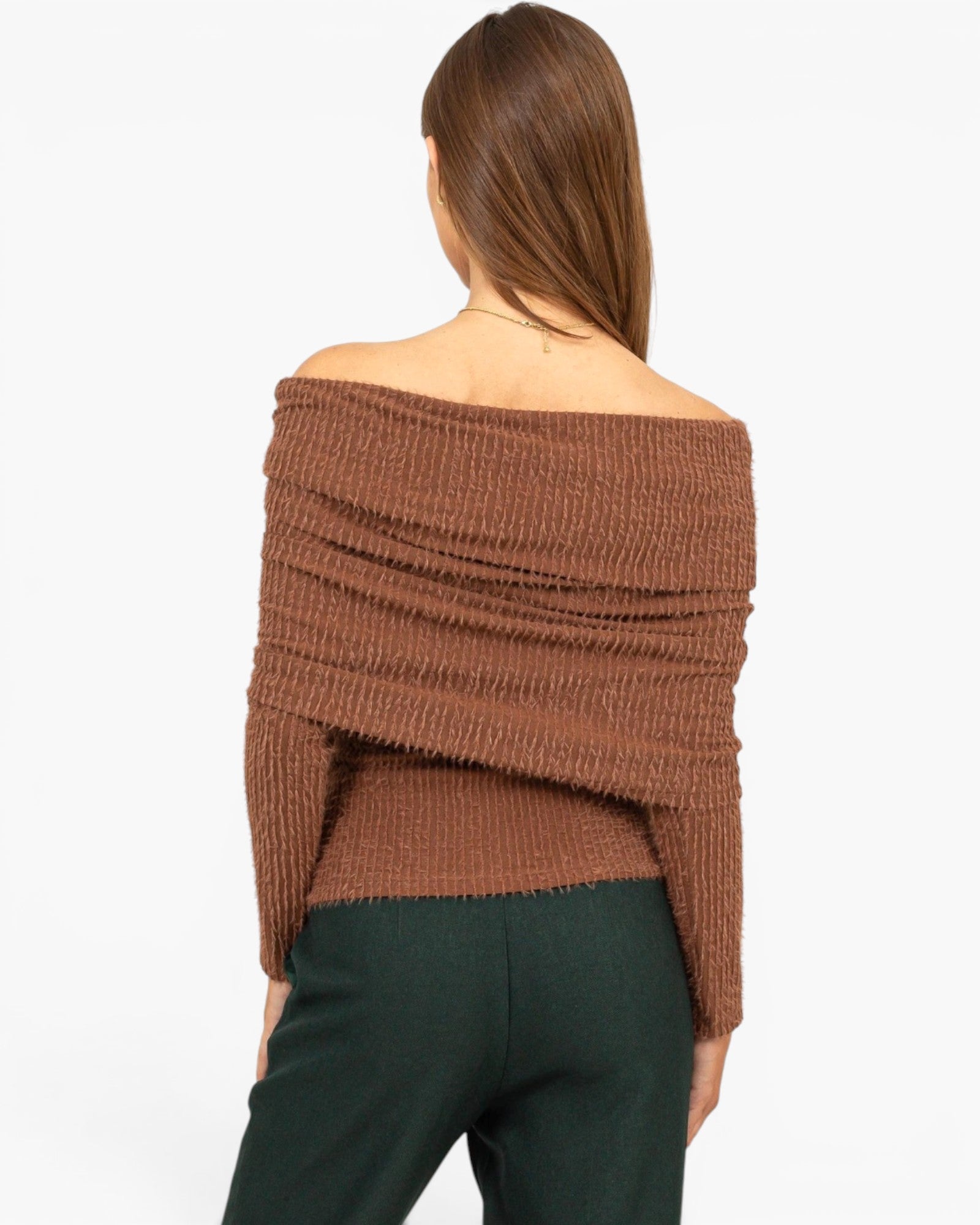 A woman shown from the back wearing a brown off-the-shoulder ribbed knit top and dark green pants against a plain white background.