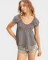 Woman wearing a black and white checkered top with denim shorts on a white background