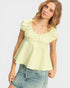 Woman wearing a light green blouse and denim shorts on a plain background