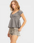 Woman wearing a checkered top and denim shorts on a plain background