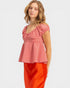 Woman wearing a red checkered top and orange pants on a white background