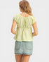 Woman wearing a light green top and denim skirt on a white background