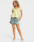 Woman wearing a light green peplum top and denim skirt on a white background