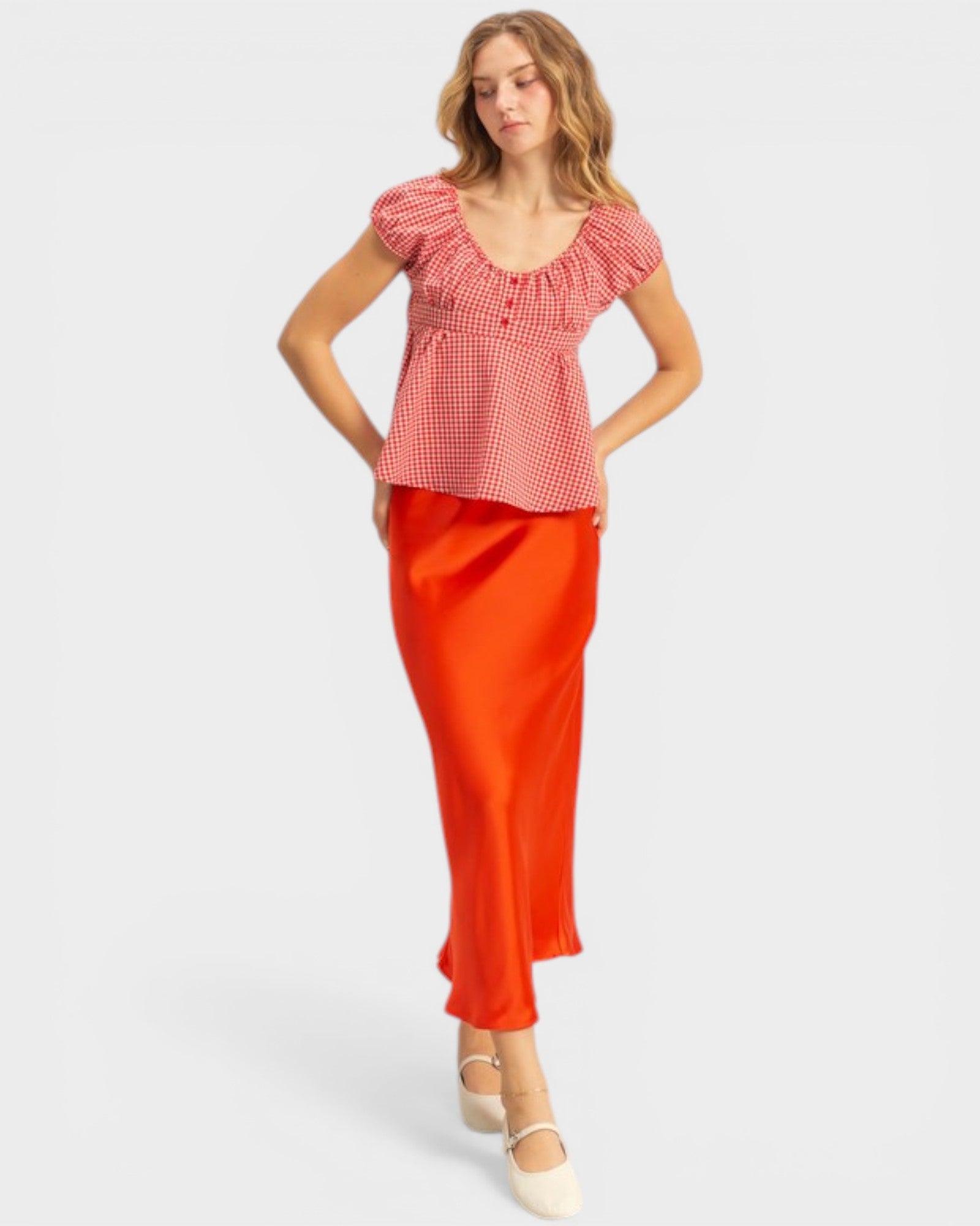 Woman wearing a red checkered top and orange pants on a white background