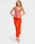 Woman wearing a red checkered top and orange pants on a white background