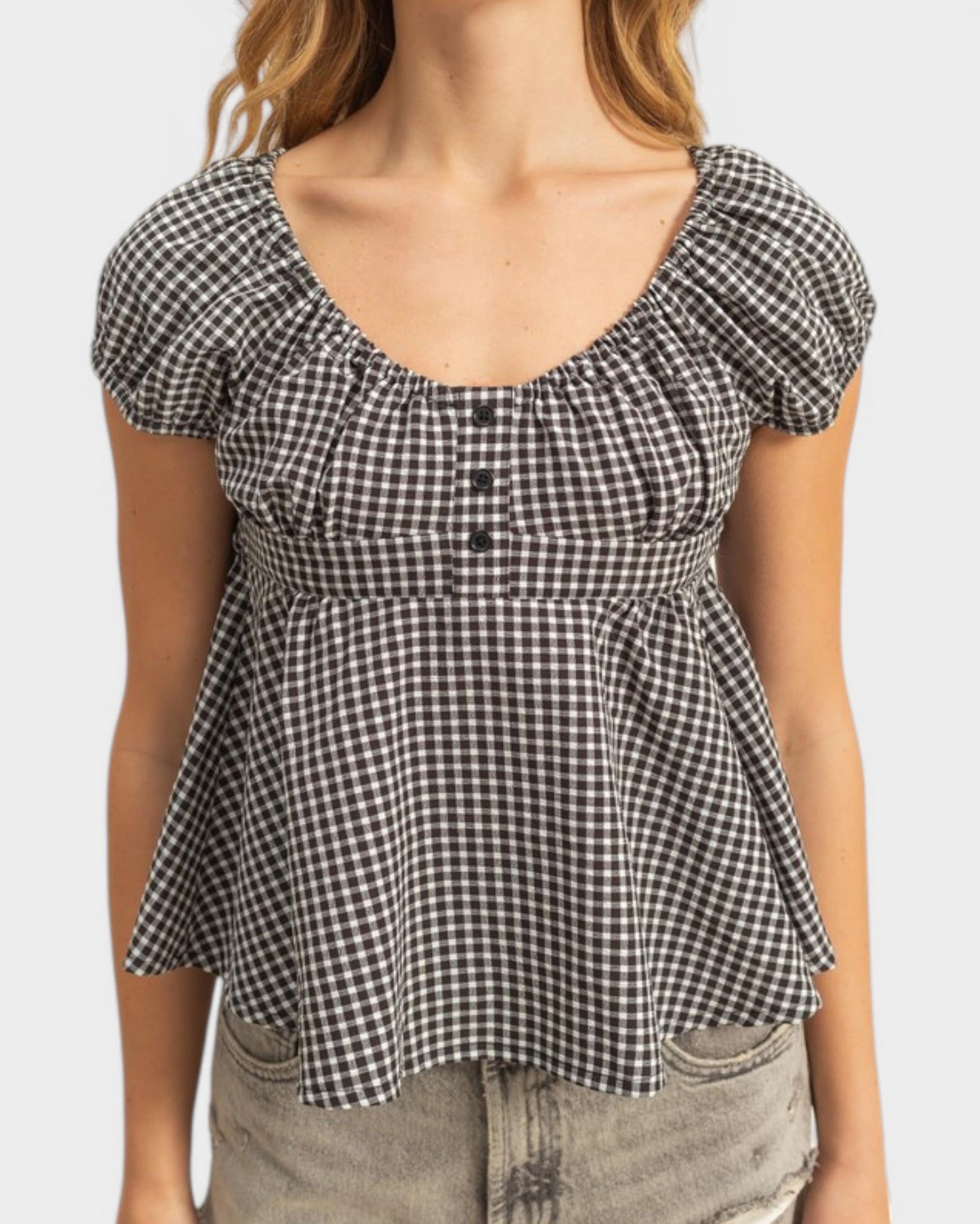 Black and white checkered peplum top worn by a person on a plain background