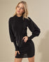 Woman wearing a black sweater dress against a beige background
