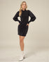 Woman wearing a black dress with white boots on a plain background