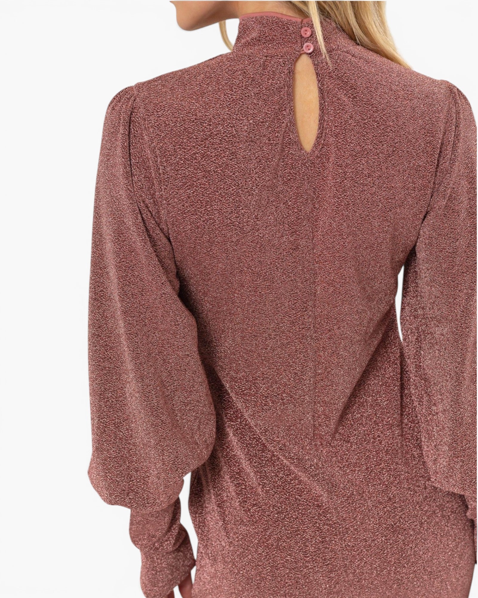 A close-up back view of a woman wearing a dusty rose long-sleeve top with a high neck, three back buttons, and a small keyhole cutout at the top. The fabric has a subtle textured sheen.