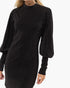 A woman wearing a black long-sleeve knit dress with a high mock neck and voluminous balloon sleeves, shown against a plain white background.