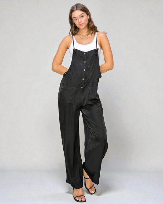 Woman wearing a black jumpsuit with white top on a plain background