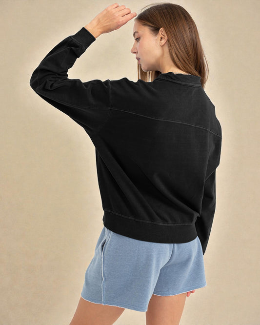Person wearing a black sweatshirt and light blue shorts on a beige background