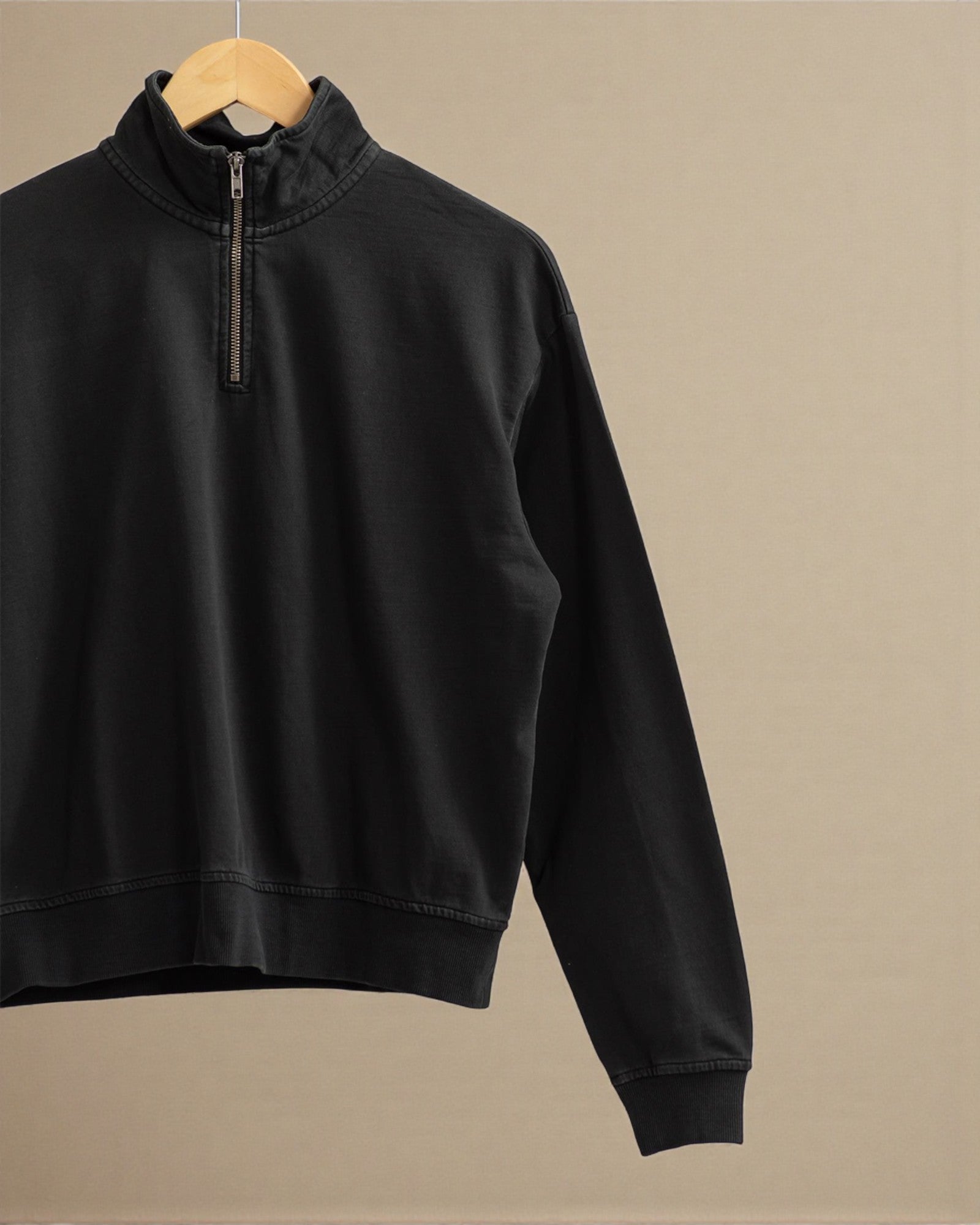 Black half-zip sweatshirt on a beige background