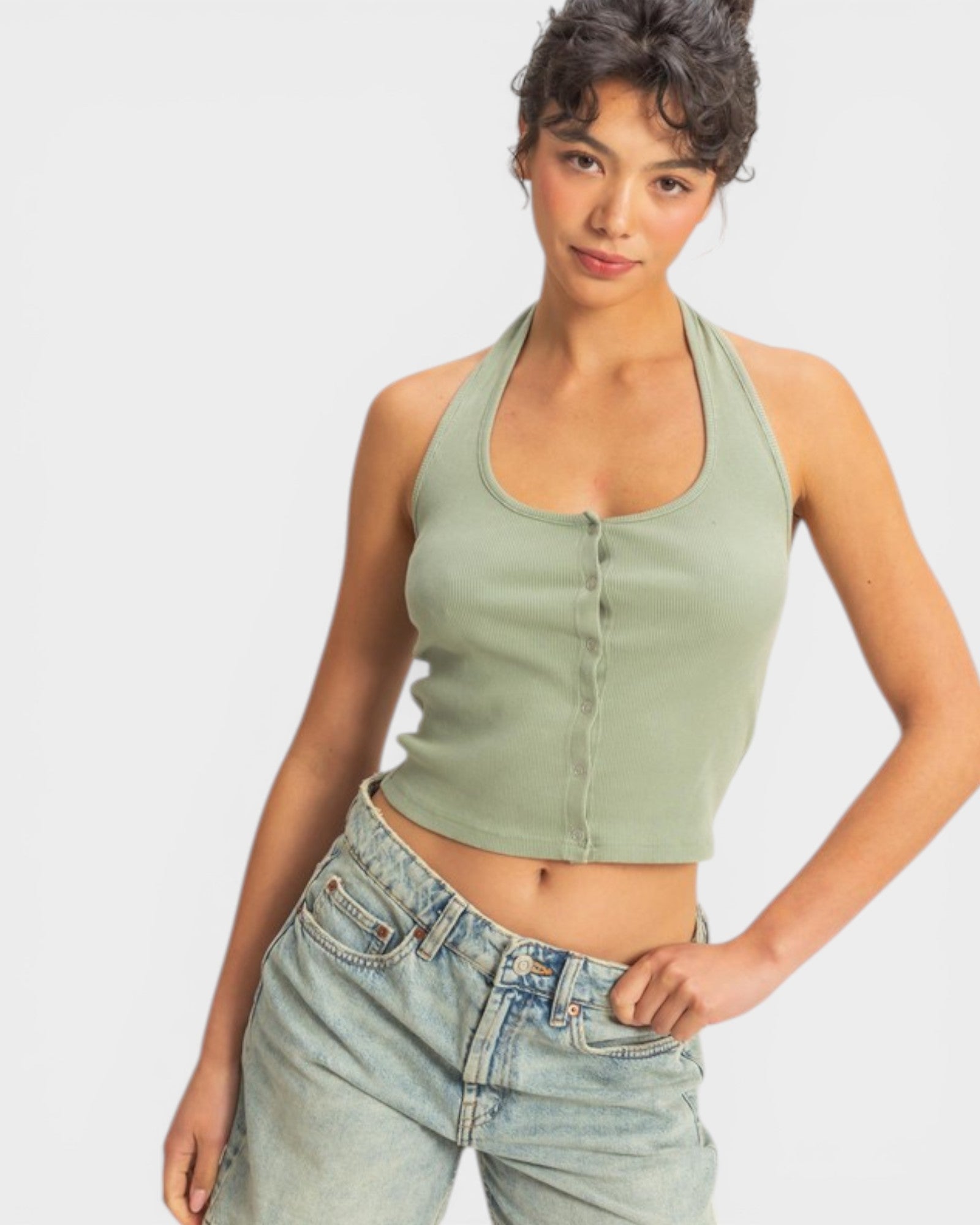 Woman wearing a green halter top and blue jeans on a white background