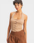 Woman wearing a beige halter top and brown pants on a white background