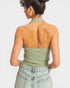 Woman wearing a green halter top and light blue jeans on a white background