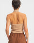Person wearing a beige halter top and brown pants on a light gray background