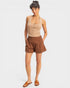 Woman wearing a beige tank top and brown shorts on a white background