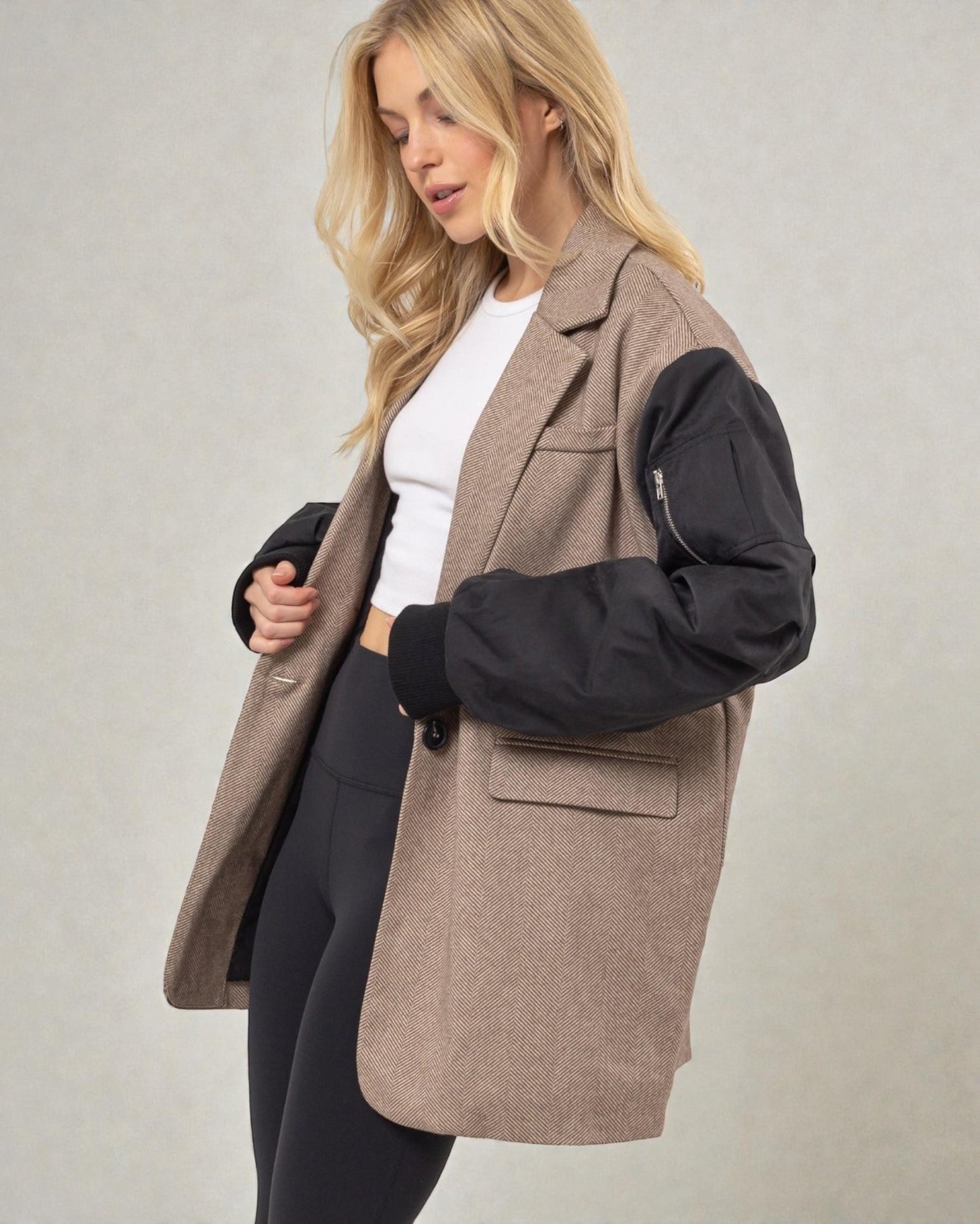 Woman wearing a brown coat with black sleeves on a plain background