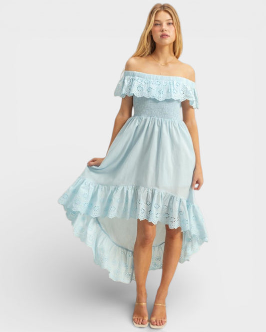 Woman wearing a light blue off-shoulder dress with lace details on a white background