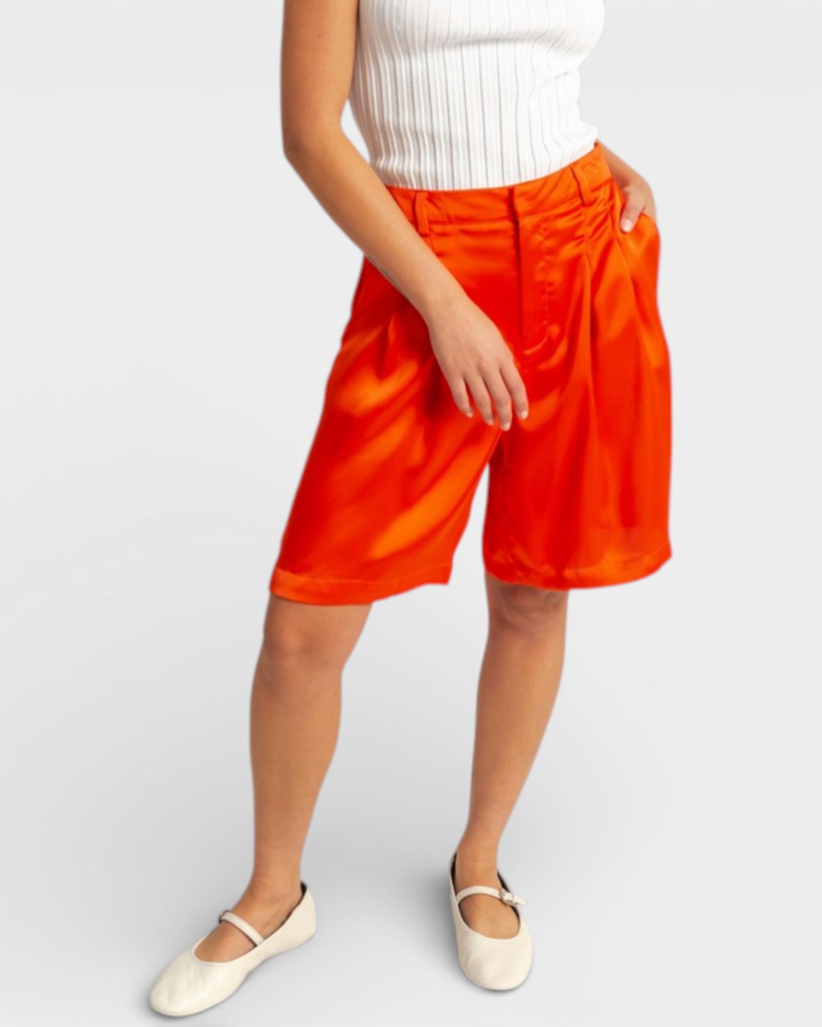 Person wearing bright orange shorts on a white background