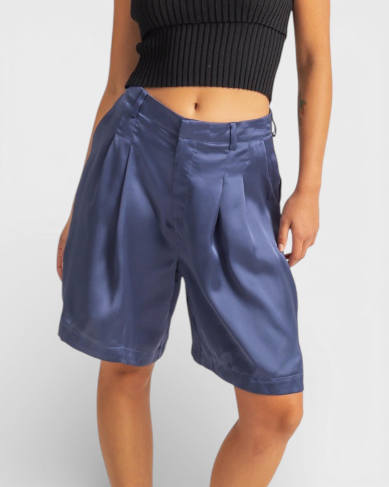 Person wearing blue shorts and a black top on a light gray background