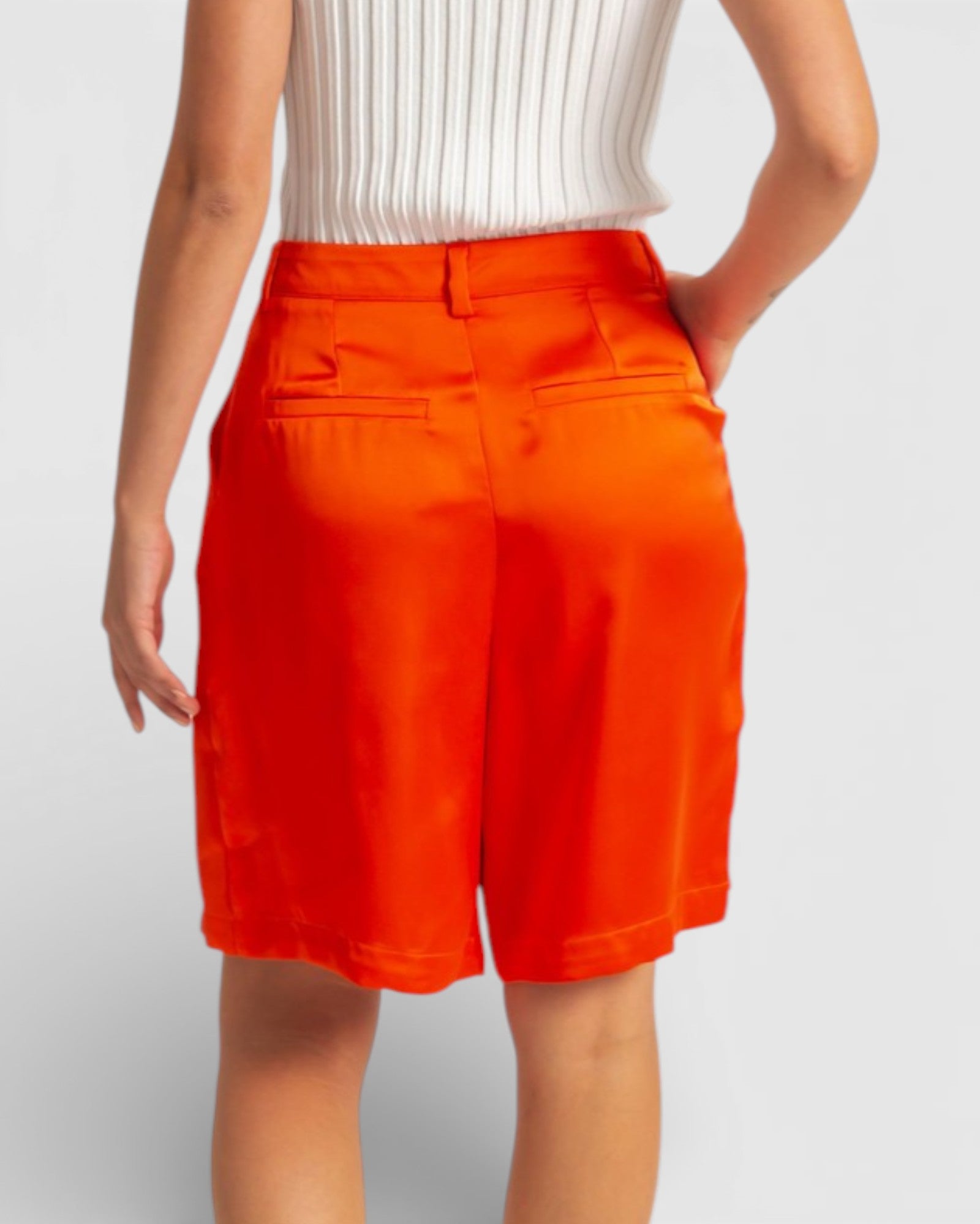 Person wearing bright orange shorts on a plain background