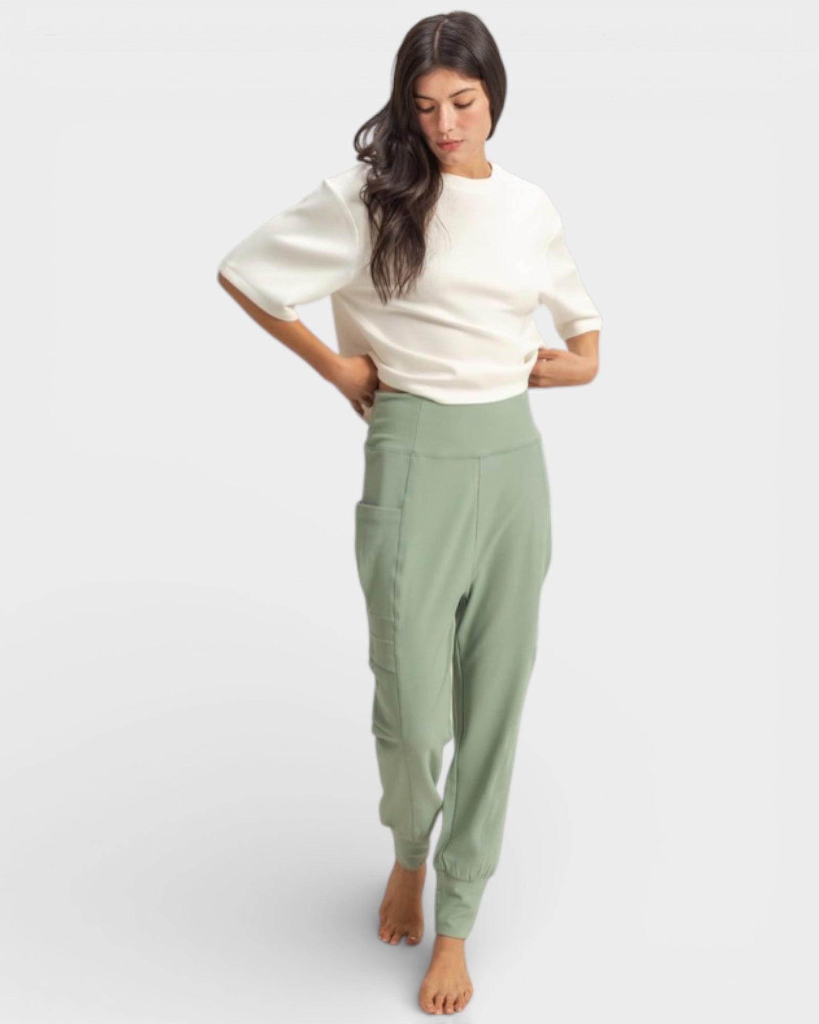 Woman wearing a white top and green pants on a white background