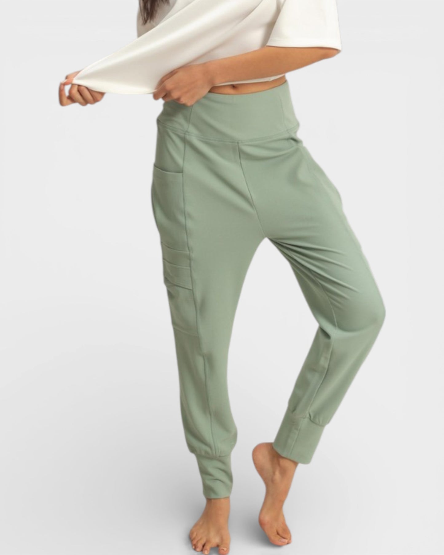 Person wearing light green jogger pants on a white background