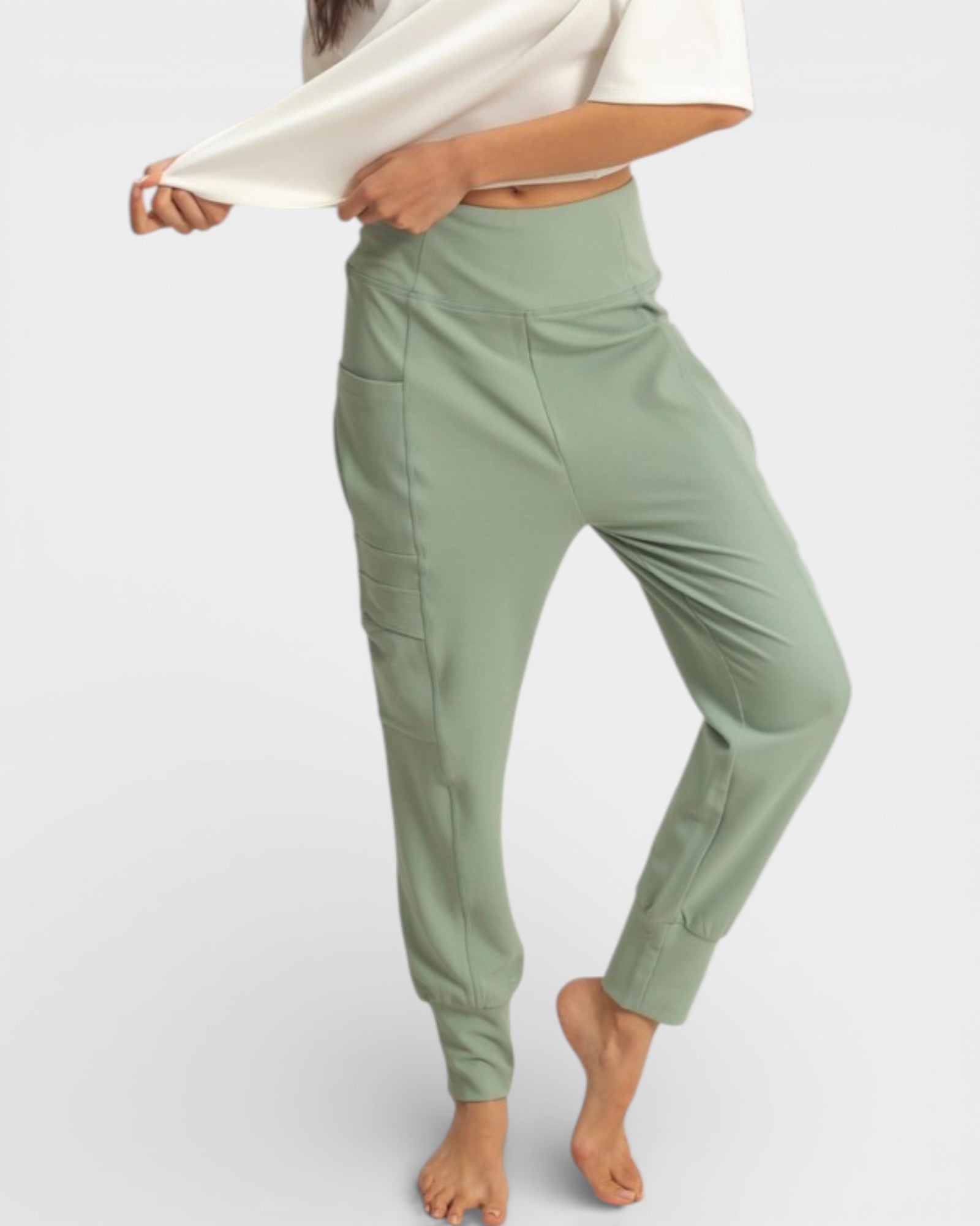 Person wearing light green jogger pants on a white background