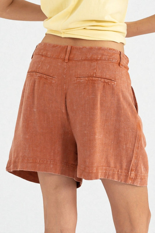 Person wearing rust-colored shorts on a white background