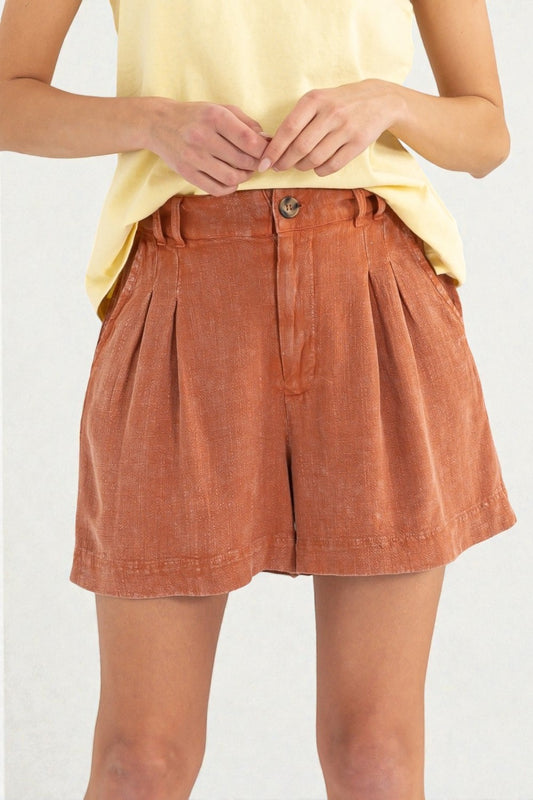 Person wearing rust-colored shorts and a yellow top on a white background
