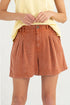 Person wearing rust-colored shorts and a yellow top on a white background
