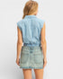 Woman wearing a light blue denim sleeveless top and skirt on a white background