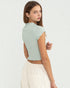 Woman wearing a light green crop top with lace details on a white background