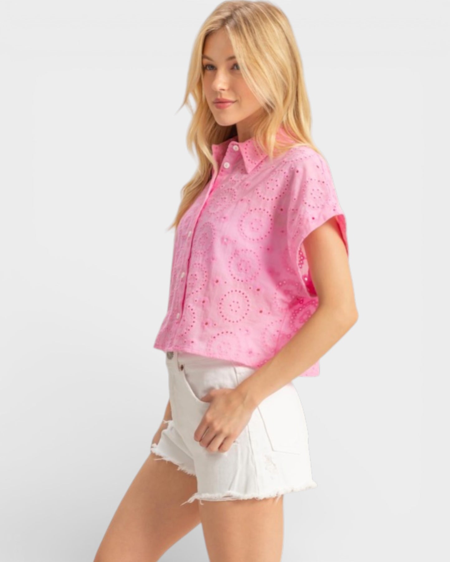 Woman wearing a pink shirt and white shorts on a plain background