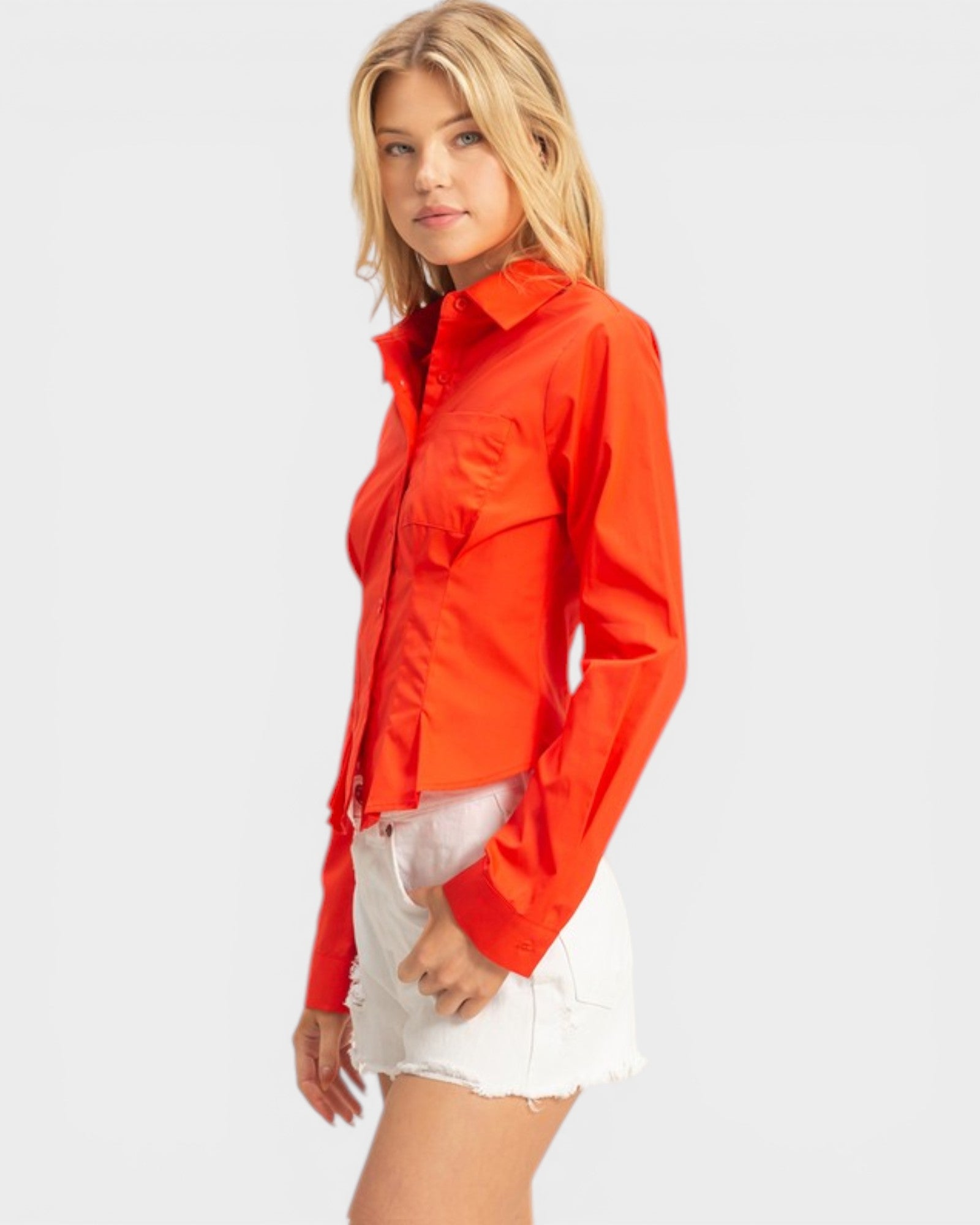 Woman wearing a bright red shirt and white shorts on a light gray background