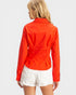 Person wearing a bright orange jacket and white shorts on a plain background