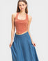 Woman wearing a rust-colored halter top and blue denim skirt on a light gray background