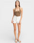 Woman wearing a brown tank top and white shorts on a plain background